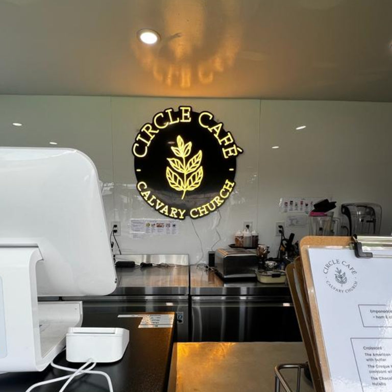 Custom Neon Sign 'Circle Cafe Calvary Church' sign mounted on the wall behind