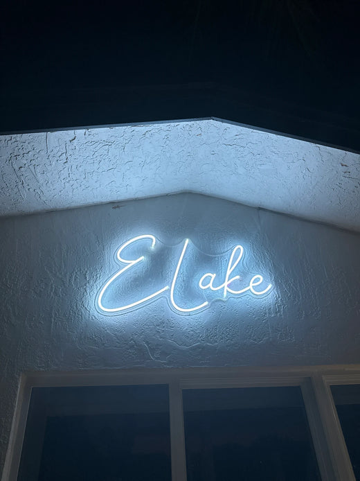 Custom neon sign with glowing white text reading Cafe on a textured blue wall at night