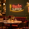 Design Preview: Stay for Supper Neon Sign in a modern neighborhood bistro with deep olive paneling, burgundy banquettes, a round marble table and fresh flowers; warmly lit evening setting. Generated room visualization, predefined colors shown.