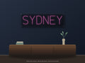 Sydney City Name Neon Sign shown above a walnut console in a styled room mockup