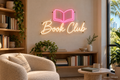 Book Club LED neon sign with soft-white script and pink open-book icon in a reading nook - design preview