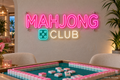 Mahjong Club LED neon sign in pink, soft white and teal above a game table - design preview